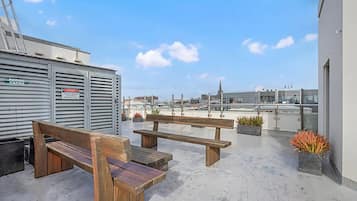 Une terrasse sur le toit, avec deux bancs en bois et des plantes en pot.