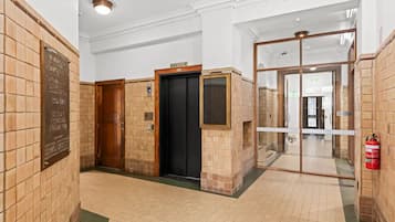 Un couloir avec un extincteur, une porte portant une plaque numérotée et une plaque fixée au mur.