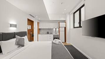 Een moderne hotelkamer met een bed, een televisie, een kitchenette en een badkamer.