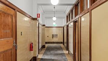 A corridor with wooden doors, a fire extinguisher, and a fire exit sign.