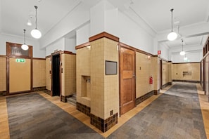 A hotel restroom with multiple stalls, wooden doors, and tiled walls. - Comfort Inn Geelong (Geelong)