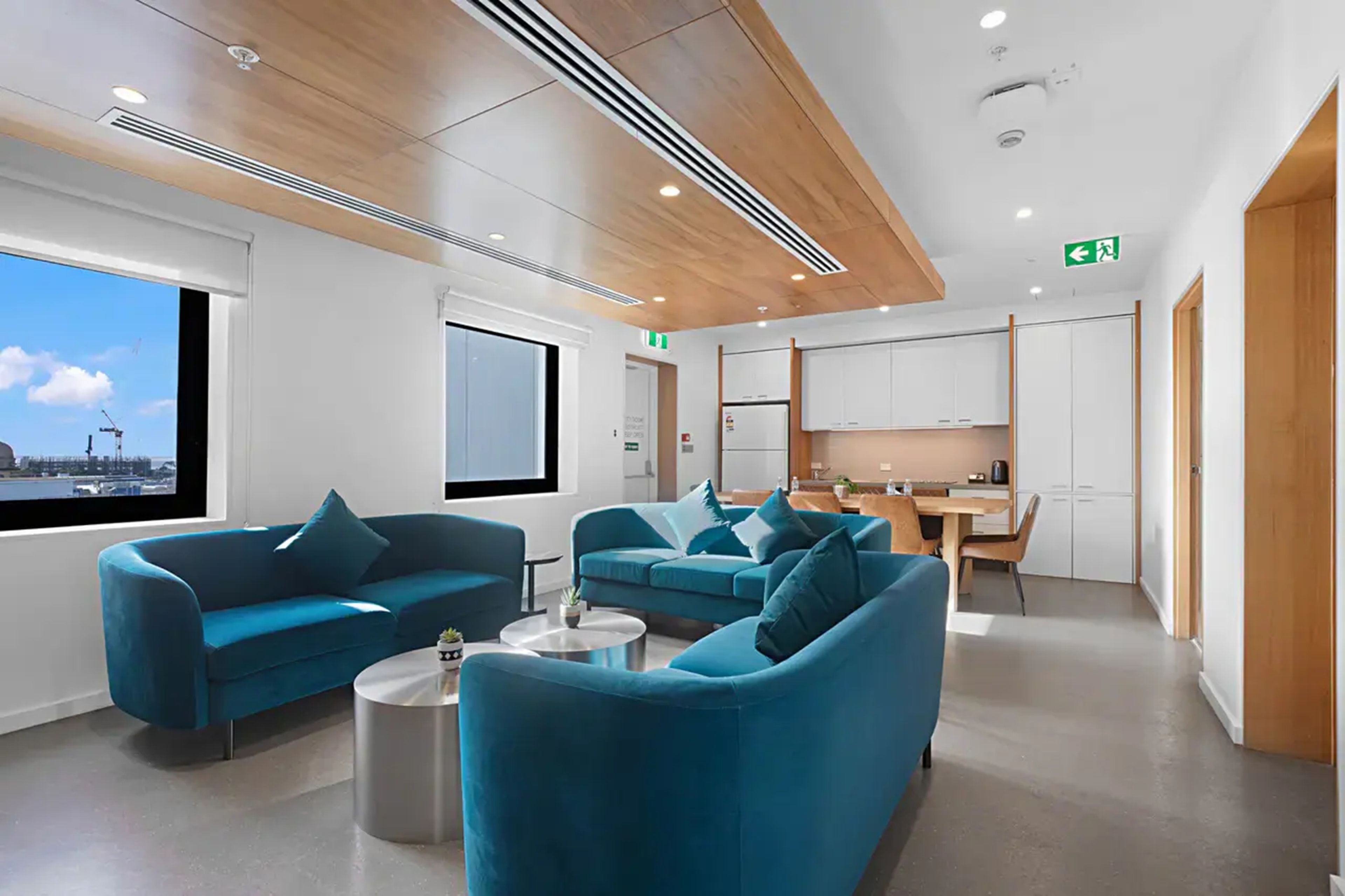 Een moderne hotellobby met smaragdgroene banken, een eetgedeelte en uitzicht op de stadshemel.