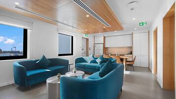 Een moderne hotellobby met smaragdgroene banken, een eetgedeelte en uitzicht op de stadshemel.