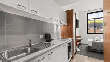 A modern kitchen with a stainless steel sink, a kettle, and a built-in oven.