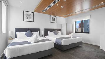 Een hotelkamer met twee bedden, een groot raam en kunstwerken aan de muur.
