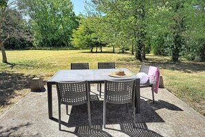 An outdoor seating area with a table and chairs, surrounded by trees and grass. - Family Chalet by Moncontour Lake (Moncontour)