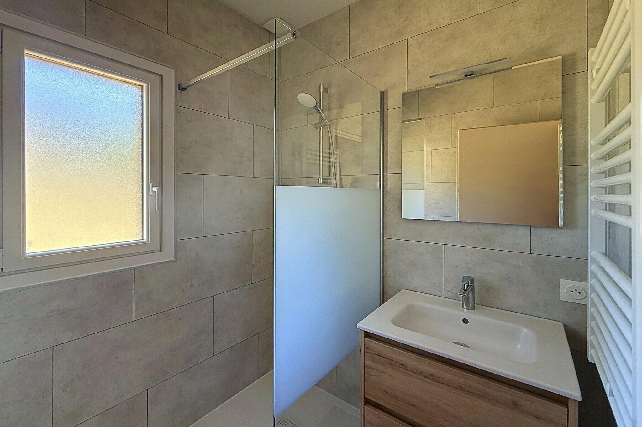 Une salle de bain moderne avec une douche, un lavabo et un miroir.