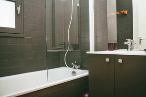 A bathroom with a bathtub, a shower enclosure, a mirror, and a cabinet. - Family Chalet by Moncontour Lake (Moncontour)