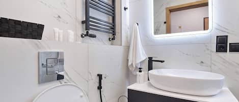 A modern bathroom with a toilet, sink, towel rack, and a mirror.