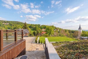 A wooden deck with stone flooring, a view of a village with houses and a church, and a clear sky. - Stylish Apartment with a Balcony | Parking (Szklarska Poręba)