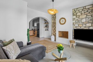 Ein modernes Wohnzimmer mit einer Couch, einem Glastisch, einem Fernseher und einer Steinwand.