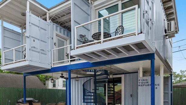 Un edificio de dos plantas con un patio cubierto, una escalera y un letrero que dice 'Find Your Repurpose'.