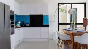 Eine moderne Küche mit weißen Schränken, einer schwarzen Arbeitsplatte und einem Essbereich mit einem Holztisch und weißen Stühlen.
