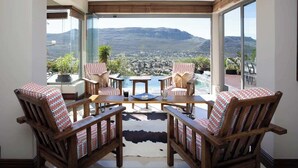 Ein Balkon mit Holzstühlen und einem Tisch, mit Blick auf eine Berglandschaft.
