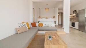 A modern living room with a sofa, a coffee table, and a kitchen area with a refrigerator. - Casa Tu Zante ❤️- center & sea view (for 6 guests) (Zakynthos)