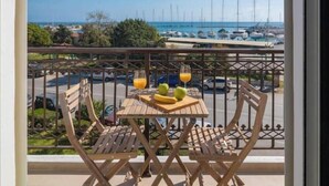 A balcony with a table and chairs, a view of the marina, and a clear sky. - Casa Tu Zante ❤️- center & sea view (for 6 guests) (Zakynthos)