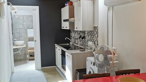 Une cuisine compacte comprenant un coin repas, un lave-linge et un ventilateur.