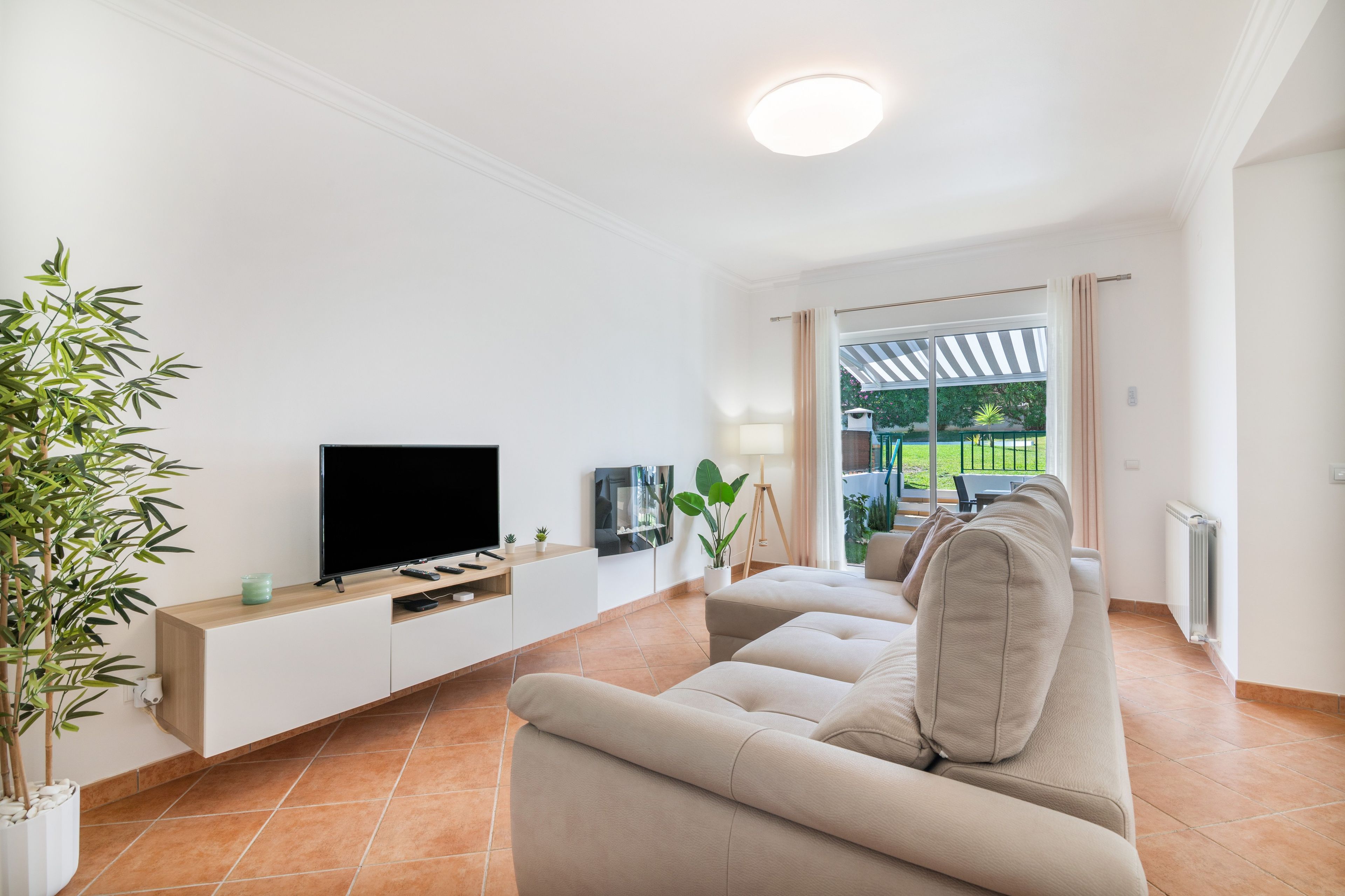 Un salon moderne avec un téléviseur à écran plat, un canapé et une plante en pot.