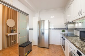 Een moderne keuken met een roestvrijstalen koelkast, een wasmachine en een magnetron.