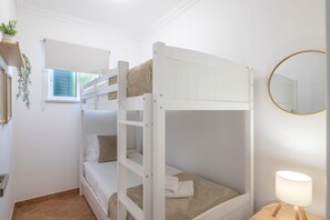 Een slaapkamer met een stapelbed, een raam, een spiegel en een bedlampje.