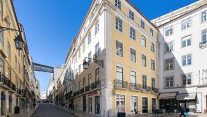 Une rue bordée d’immeubles, un piéton et un ciel dégagé.