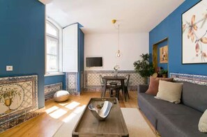 Ein Wohnzimmer mit Sofa, Couchtisch, Fernseher und einem Essbereich mit Stühlen und Tisch.