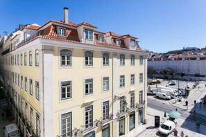 Ein mehrstöckiges Gebäude mit gelber Fassade, zahlreichen Fenstern und einem roten Ziegeldach.