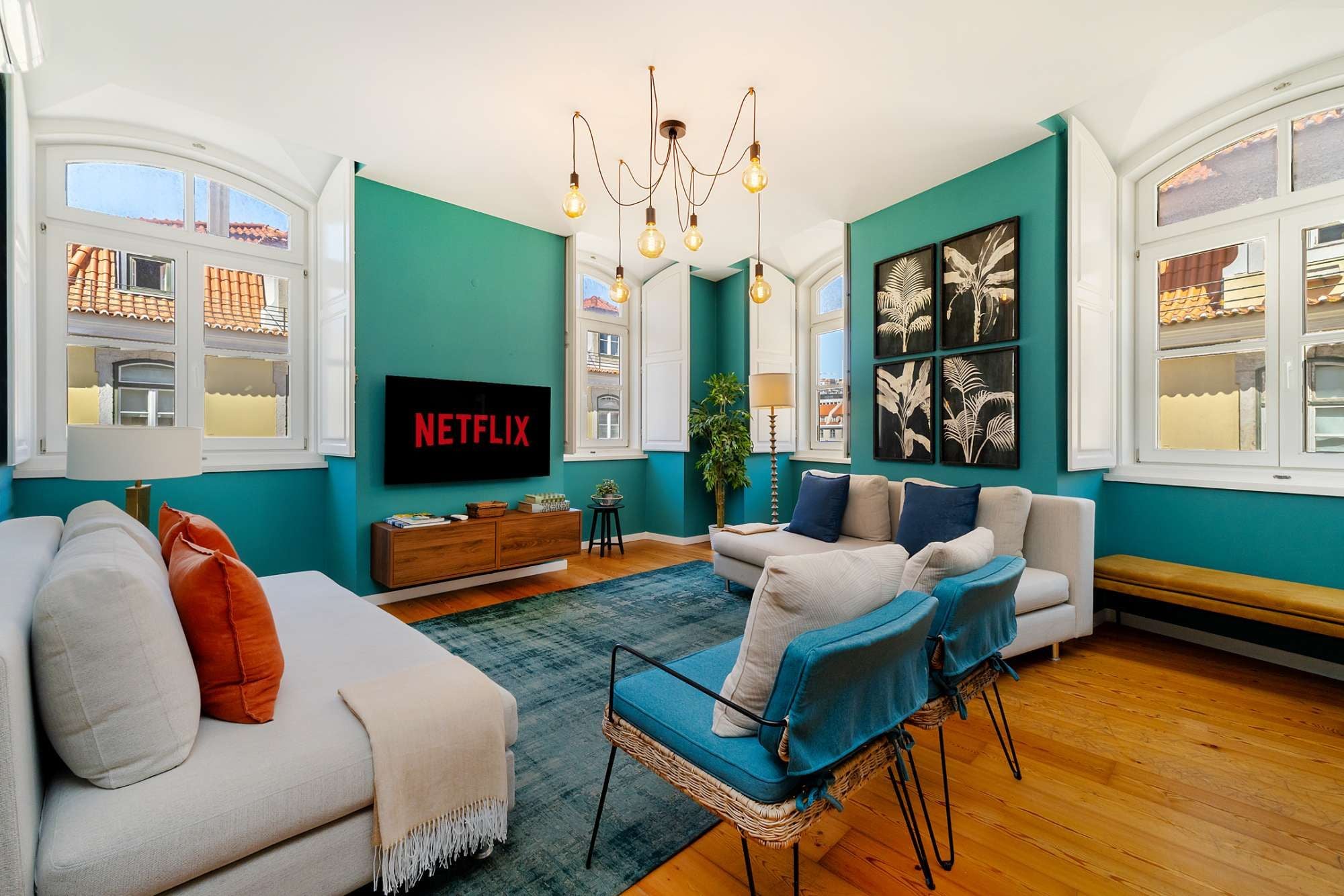 Een woonkamer met een bank, fauteuils, een salontafel, een televisie en kunstwerken aan de wanden.