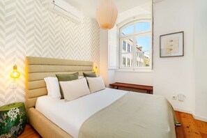 A bedroom with a bed, bedside lamps, a window, and a view of buildings. - Authentic Central Lisbon Gem with Unique Design (Lisboa)