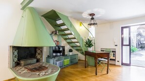 A living room with a green spiral staircase, a fireplace, a television, and a dining table. - Secret Loft in Trastevere - Moro (Rome)