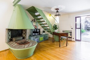 Ein Wohnzimmer mit einer grünen Wendeltreppe, einem Kamin, einem Fernseher und einem Esstisch.