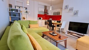 A modern living room with a green sofa, a wooden coffee table, and a flat-screen TV. -  A beautiful cozy apartment very close to the beach and to all amenities. (Durrës County)