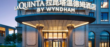 La entrada del hotel La Quinta by Wyndham, con un diseño moderno y señalización iluminada.