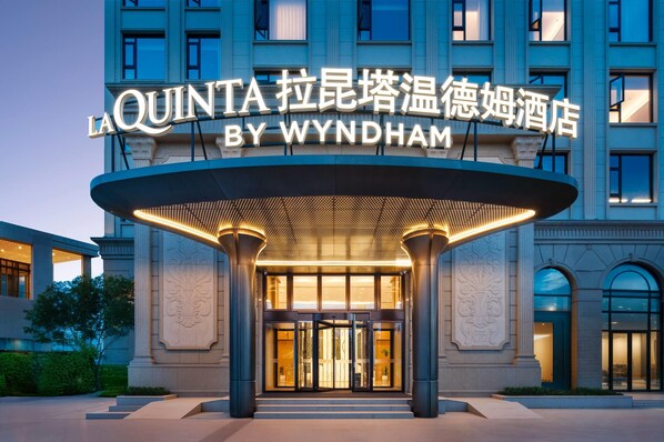 Entrada do hotel La Quinta by Wyndham, com design moderno e sinalização iluminada.