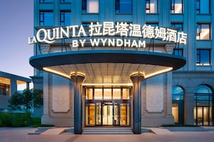 La entrada del hotel La Quinta by Wyndham, con un diseño moderno y señalización iluminada.