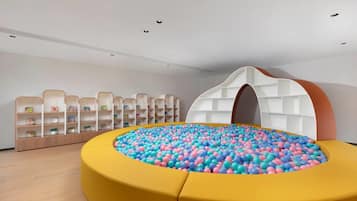 A play area with a ball pit and shelves of children's books.