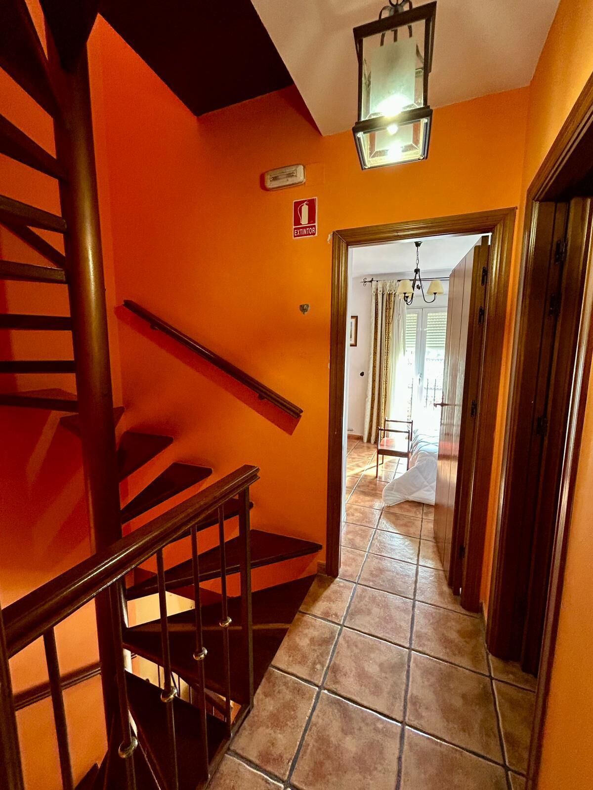 Un escalier avec une rampe menant à une pièce dont le sol est recouvert de carreaux et qui possède une porte.