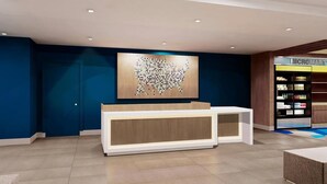 Una recepción de diseño moderno, una obra de arte colgada en la pared y una estantería con diversos objetos.