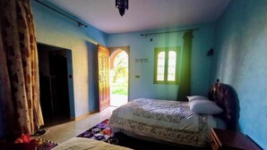A bedroom with a bed, a window, a door, and a hanging light fixture. - Gite DAR UL (Er-Rteb)