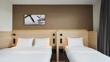 A hotel room with two beds, a headboard with integrated lighting, a wall-mounted artwork, and a curtain.