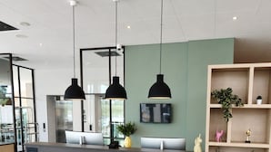A reception desk with a modern design, a flat-screen TV, and a wooden shelving unit with decorative items.