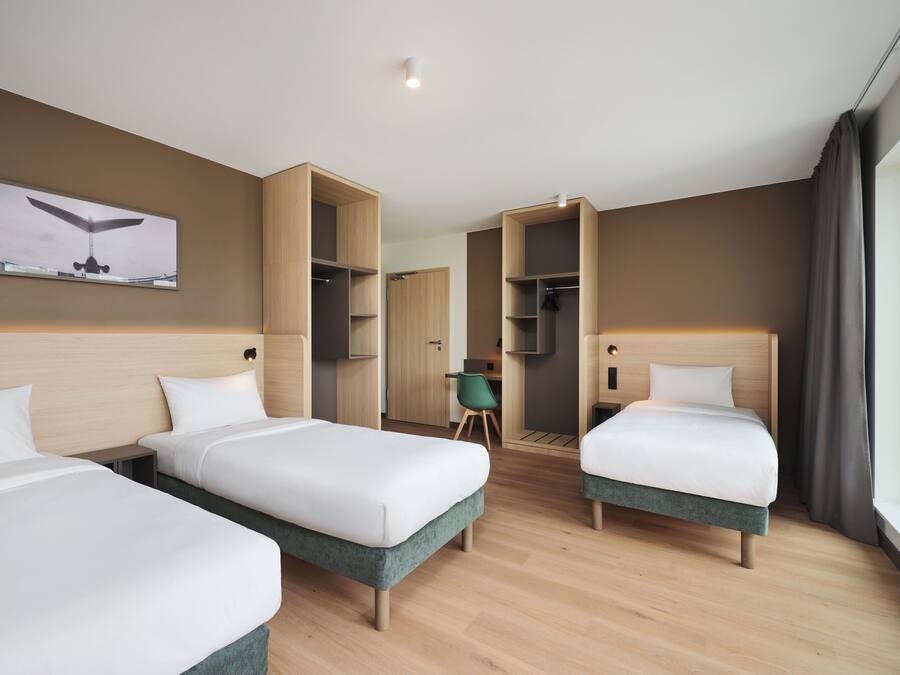 A hotel room with three beds, a desk, and a wardrobe.