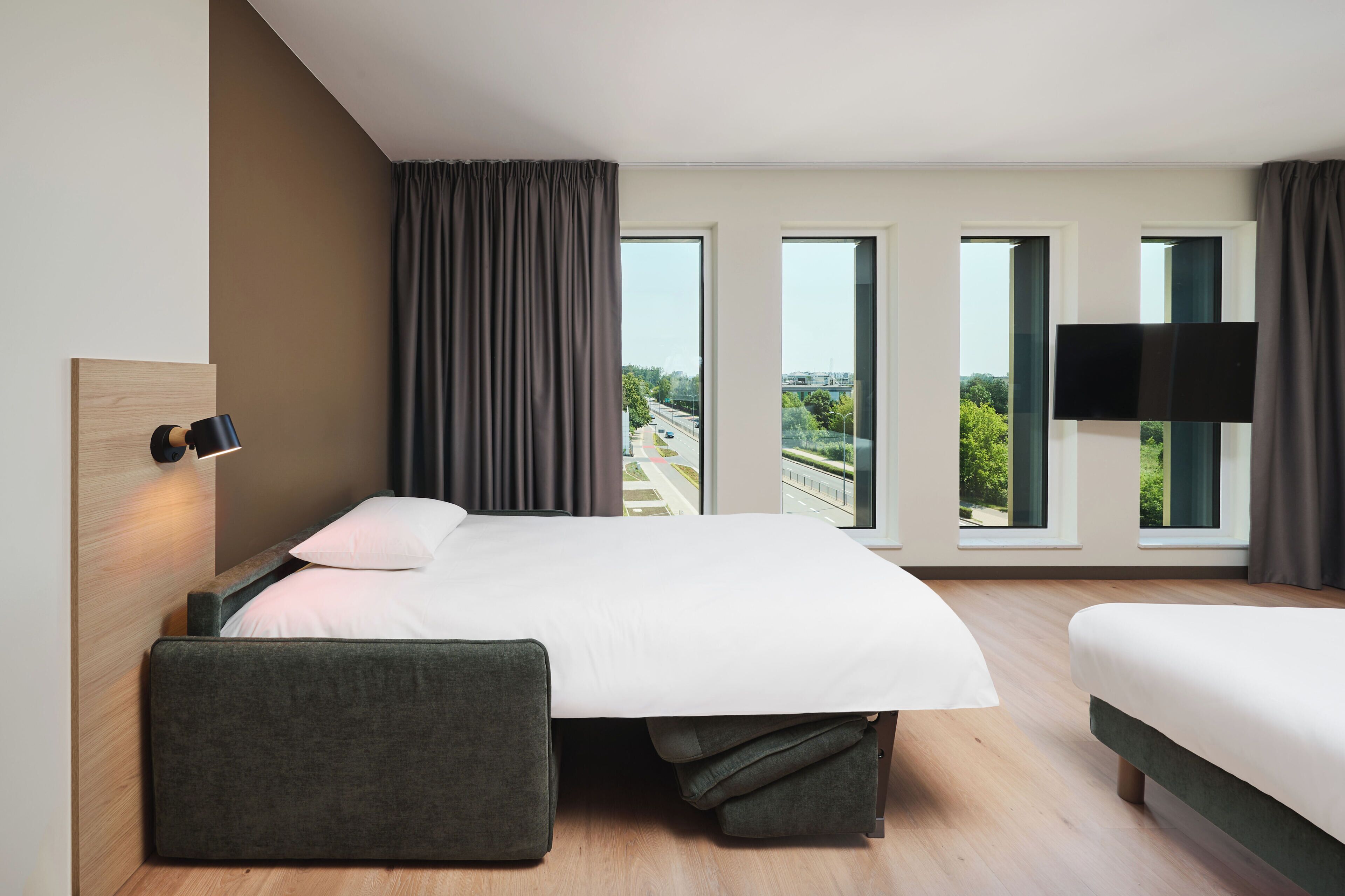 Ein modernes Hotelzimmer mit einem großen Bett, einer Sitzecke und einem Fernseher.