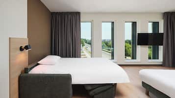 A modern hotel room with a large bed, a seating area, and a TV.