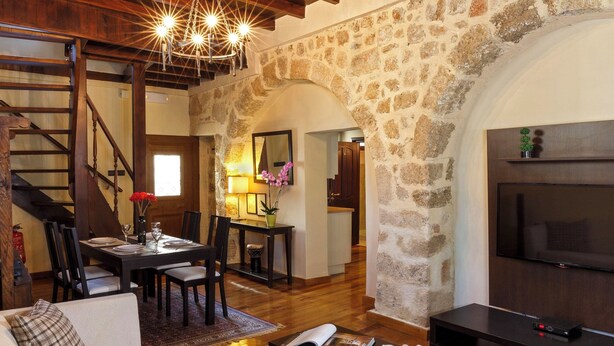 Un salón espacioso con techo alto, paredes de piedra, chimenea, televisor y escalera.