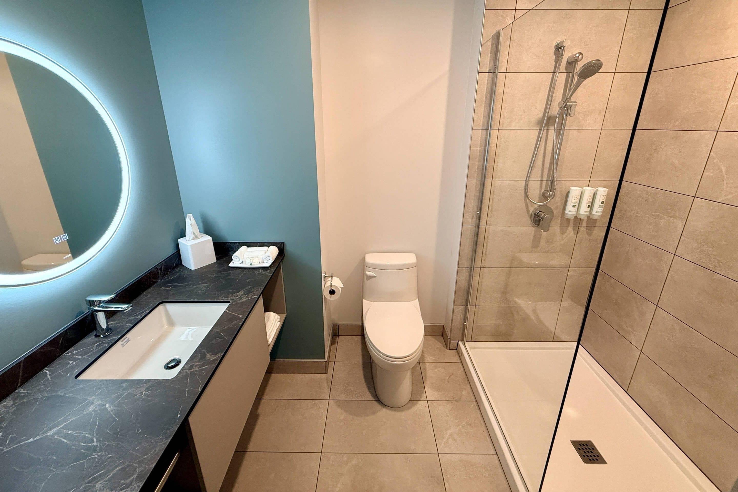 Un baño moderno con lavamanos, inodoro y zona de ducha.