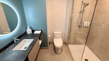 Un baño moderno con lavamanos, inodoro y zona de ducha.
