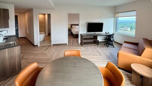 Habitación de hotel moderna con comedor, televisor y un ventanal con vistas.