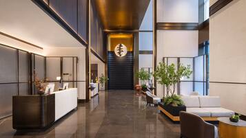 A modern lobby with a reception desk, seating area, and a large decorative wall.