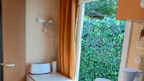 Una kitchenette compacta con estufa, cafetera y una mesita con microondas.
